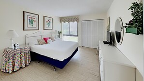 Un dormitorio con cama, mesita de noche, lámpara y ventana con persianas.