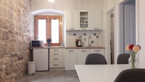 Eine kleine Küche mit Steinwand, einem kompakten Spülbecken, einer Mikrowelle und einem Essbereich mit Tisch und Stühlen.