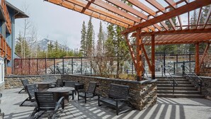 An outdoor patio with stone walls, wooden benches, and a pergola structure. - Spacious (700 sqft) 1 Bedroom/1 Bath cozy Condo /Pool & Hot tubs (Canmore)