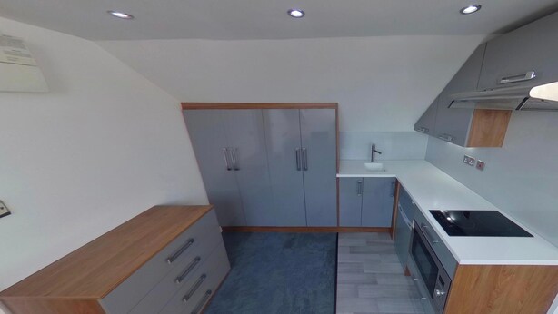 A compact kitchen with grey cabinets, a wooden countertop, and a built-in stove.
