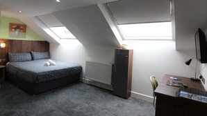 A bedroom with a bed, a desk, a radiator, and skylights.
