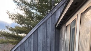 A wooden deck with two wicker chairs and a small round table. - Cozy Killington Mountain View Condo (Killington)