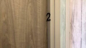 Ein Zimmer mit einer Holztür, einer weißen Wand und der Nummer 2 auf der Tür.