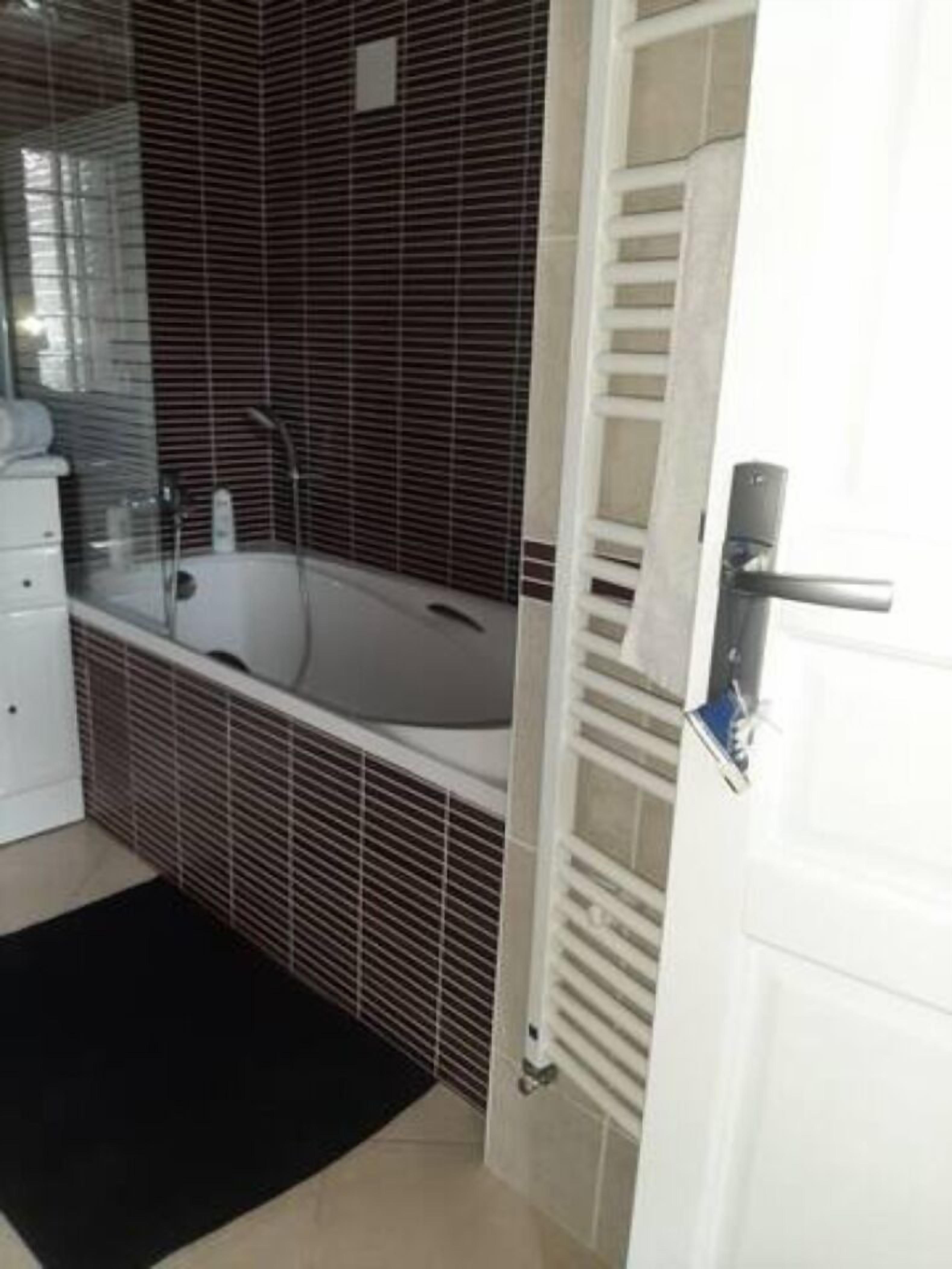 A modern bathroom with a bathtub, a white sink, and a towel rack.