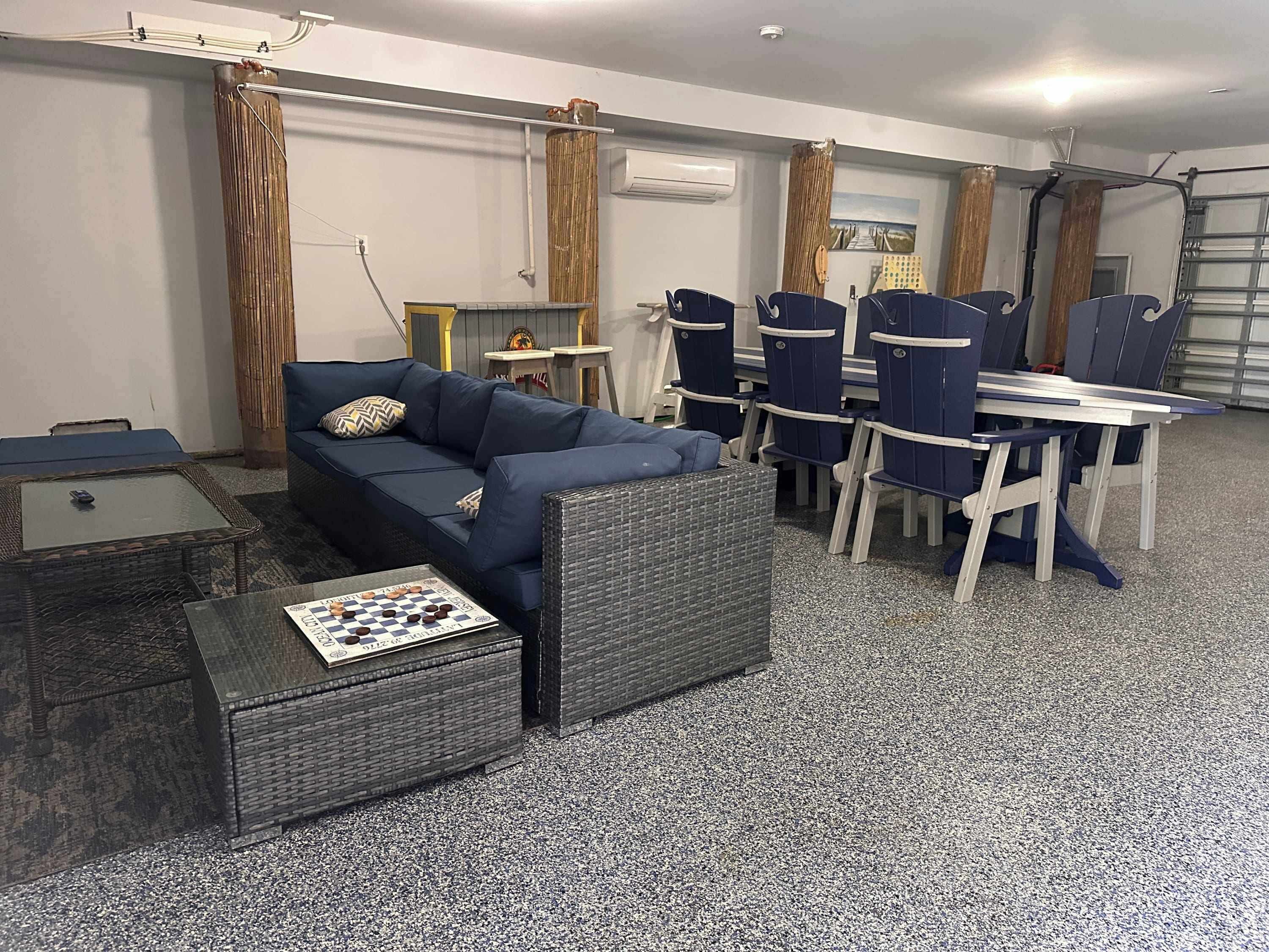 A living room with a blue sofa, a coffee table with a chessboard, and a dining area with blue chairs and a white table.