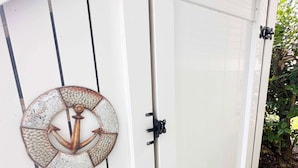 Une porte blanche ornée d’une ancre en métal et dotée d’un loquet noir.