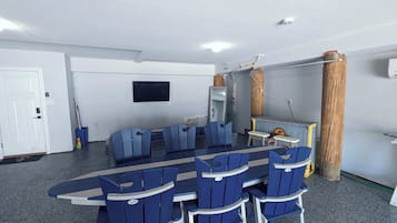 Relax in comfort with a long table and six chairs, a flat-screen TV, and a convenient side table with a lamp.