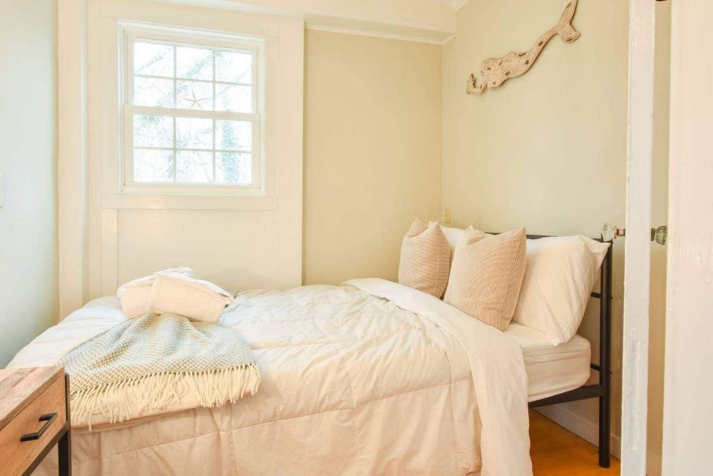 Un dormitorio con cama, ventana y un adorno en la pared.
