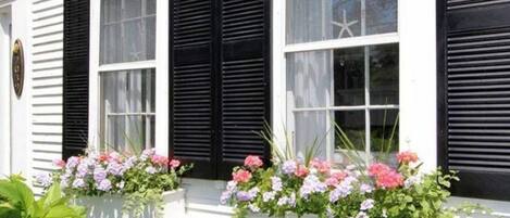 A white building with black shutters and flower boxes on the windowsills.