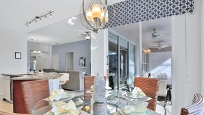A modern dining area with a glass table, wicker chairs, and a decorative centerpiece.