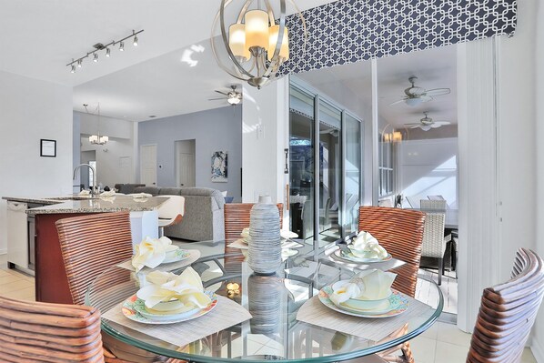 Un comedor moderno con una mesa de vidrio, sillas de mimbre y un centro decorativo.