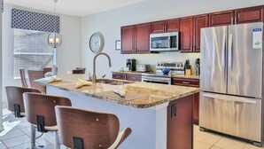 A modern kitchen with a central island, stainless steel appliances, and wooden cabinets.