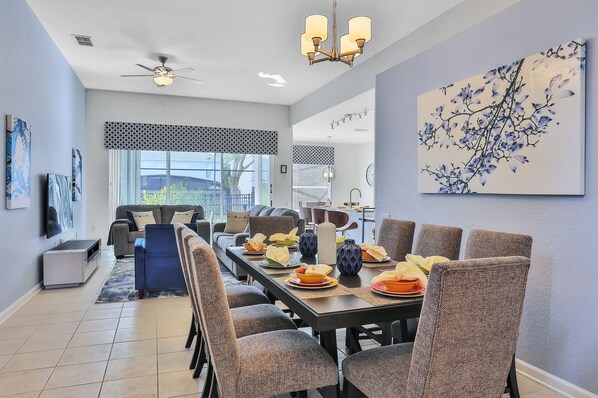A dining area with a long table set for six, surrounded by chairs.