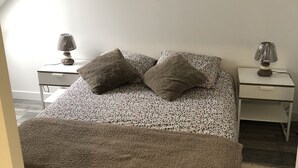 A bedroom with a bed, two nightstands, and two wall-mounted lamps.