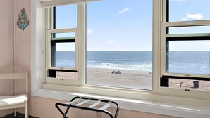 Une pièce dotée d’une grande fenêtre donnant sur une plage, d’une petite table et d’un élément décoratif mural.