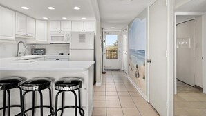 Une cuisine moderne avec des meubles blancs, un grand îlot central doté de tabourets, un four à micro-ondes et un grille-pain.