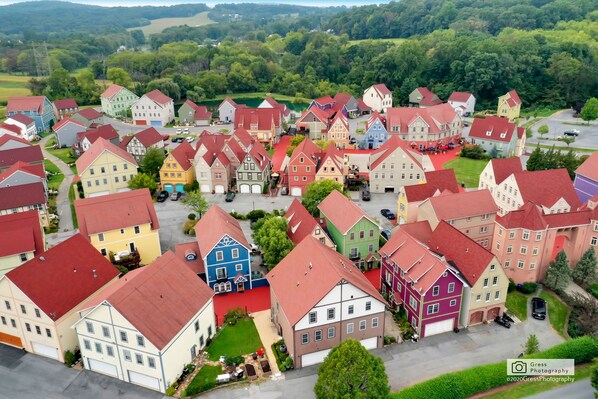 Un quartier r ésidentiel avec des maisons aux couleurs vives, une rue principale et de nombreux espaces verts environnants.