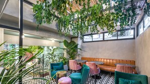 Un espacio interior moderno con suelo de estampado geométrico, asientos tapizados en verde y plantas colgantes.