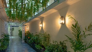 Un pasillo con plantas colgantes, luces fijadas a la pared y suelo de baldosas.