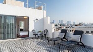 Una terraza en la azotea con piso estampado, un comedor con sillas y mesa, y un área de descanso con sillones.