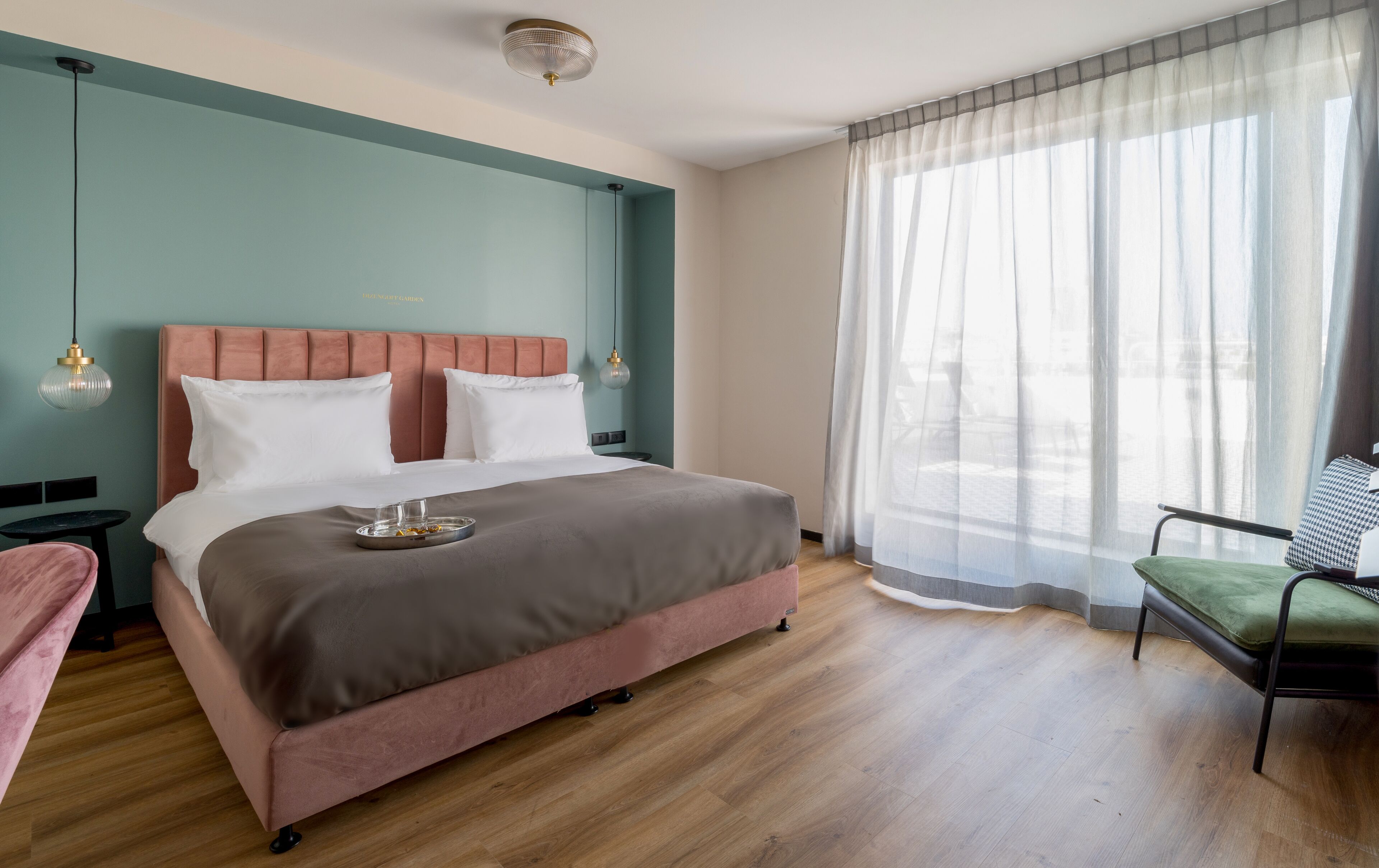 A modern bedroom with a large bed, a bedside table, a chair, and a window with sheer curtains.
