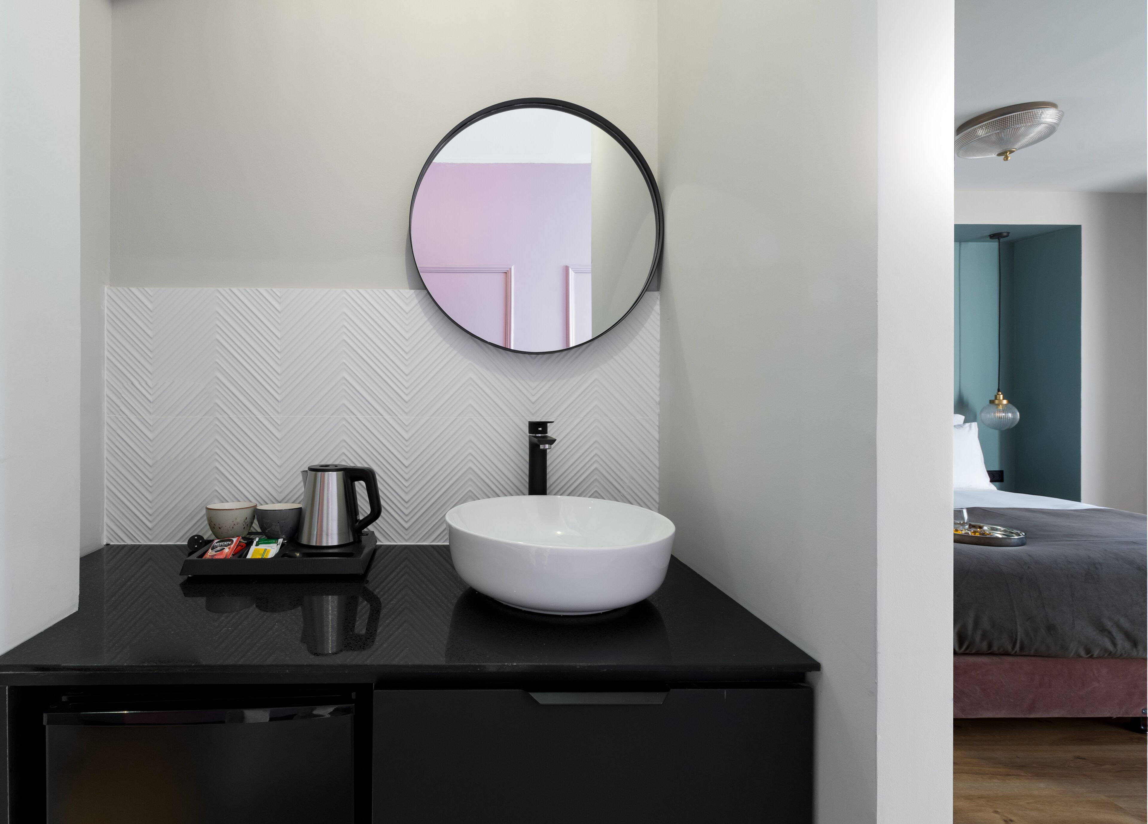 A modern bathroom with a round mirror, a white sink, and a black countertop.