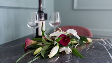 Una mesa con un ramillete de flores, dos copas de vino y una botella.
