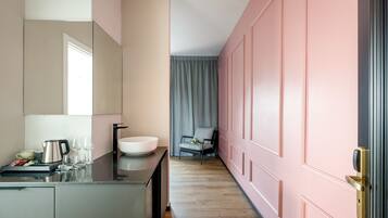 Ein modernes Hotelzimmer mit einem großen Spiegel, einem Waschbecken, einem Stuhl und einer Tür mit Schlüsselsperre.