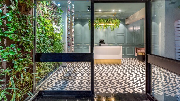 Un interior moderno con suelo estampado, una recepción y una pared verde con plantas.