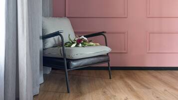 A chair with a checkered cushion and a bouquet of flowers, positioned against a pink wall with paneling.