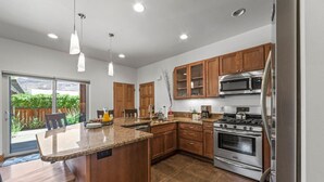 Una cocina moderna con encimeras de granito, electrodomésticos de acero inoxidable, armarios de madera y una isla grande.