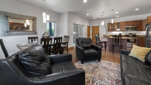 Una sala de estar moderna con muebles de cuero, un comedor y una cocina con armarios de madera y electrodomésticos de acero inoxidable.