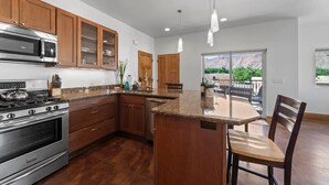 Une cuisine moderne avec des meubles en bois, des appareils en acier inoxydable et un grand îlot central doté de sièges.