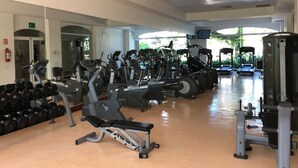 Une salle de sport équipée de divers appareils d’entraînement, d’haltères et de matériel de cardio.