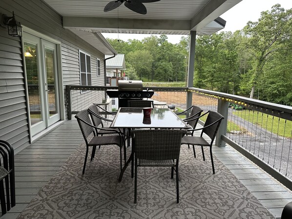 Un patio techado con mesa y sillas, una parrilla y vistas del entorno.