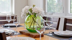 A dining table set with plates, cutlery, and wine glasses, with a green vase containing white flowers in the center. - 57 Robber`s Roost #4 - Lionsback (Moab)