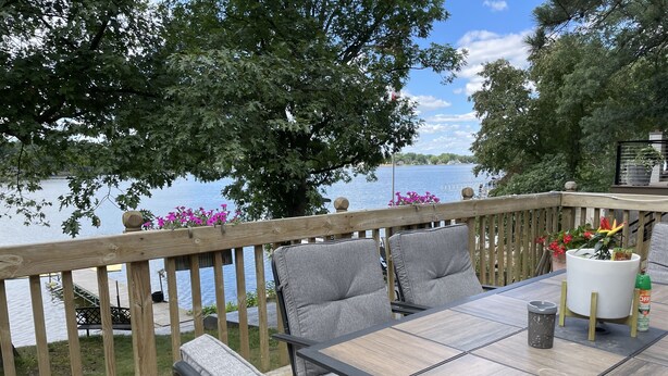 Eine Terrasse mit Tisch und Stühlen mit Blick auf ein Gewässer.