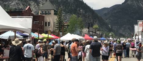 A crowded street with tents and people, set against a mountainous backdrop.