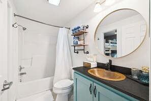 Un baño con bañera, inodoro, lavamanos y espejo.