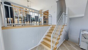 A staircase with wooden steps and a metal railing, leading to an upper floor. - Oceanfront 3BR/3BA with direct ocean views, private parking and bikes included (Cape May)