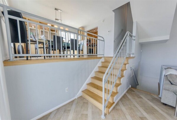 A staircase with wooden steps and a metal railing, leading to an upper floor. - Oceanfront 3BR/3BA with direct ocean views, private parking and bikes included (Cape May)