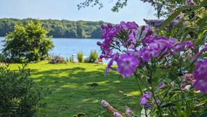 Een tuin met paarse bloemen en uitzicht op een meer.