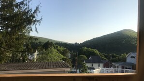 Asuinalue, jossa on taloja, taustalla kumpuileva mäki ja edessä puinen terassi.