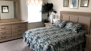 Un dormitorio con cama, cómoda, espejo y cuadros en la pared.