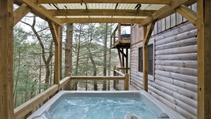 Un jacuzzi en una cabaña de madera con vista a un bosque.