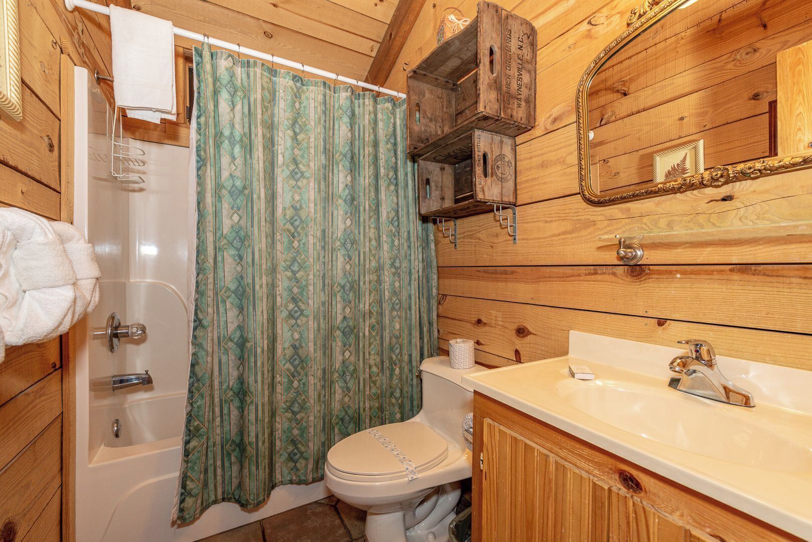 A wooden cabin bathroom with a shower, toilet, and sink.