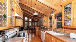 Cocina de cabaña de madera con estufa, fregadero y comedor.