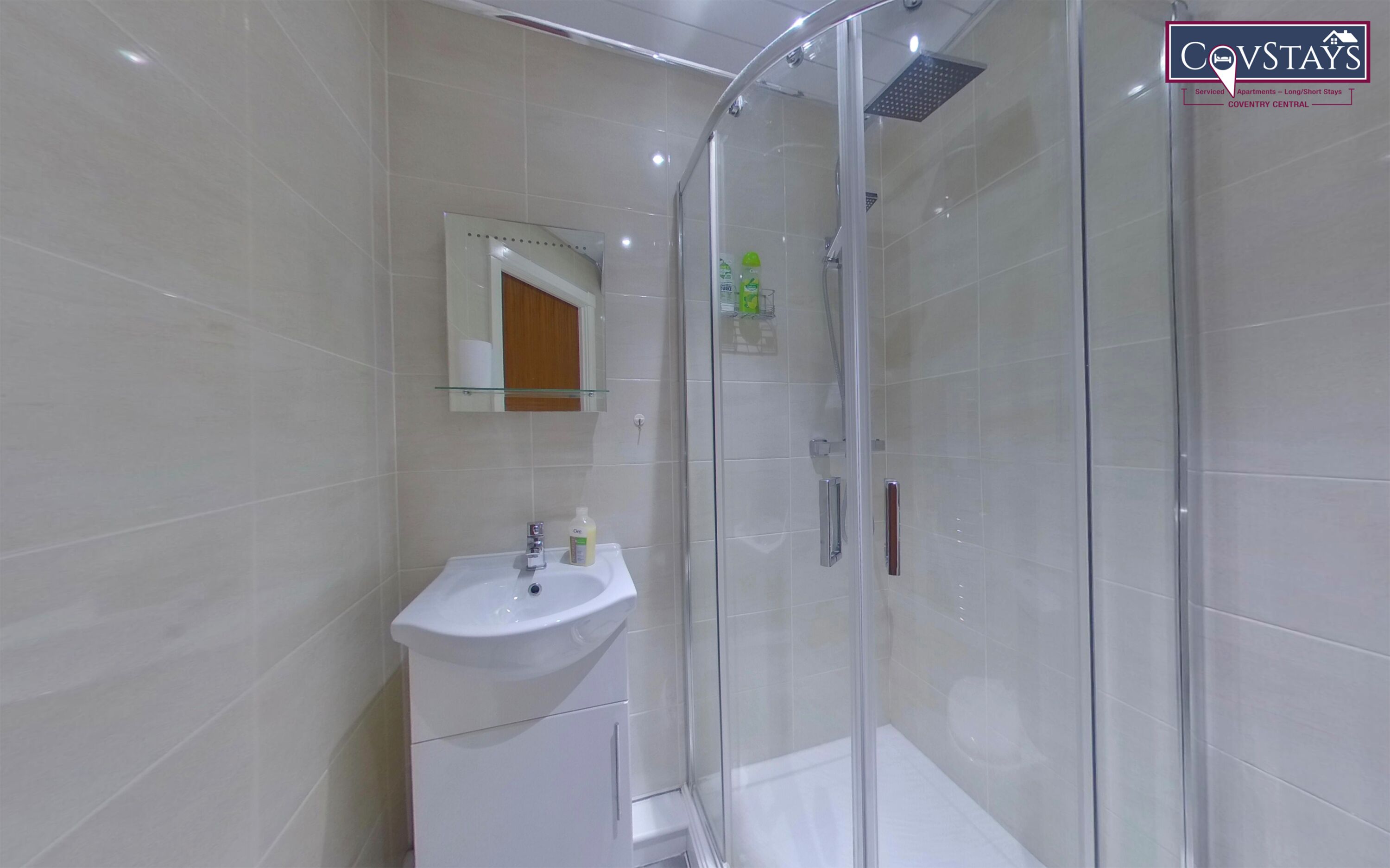 Un baño moderno con cabina de ducha de vidrio, un lavabo blanco y un espejo encima.