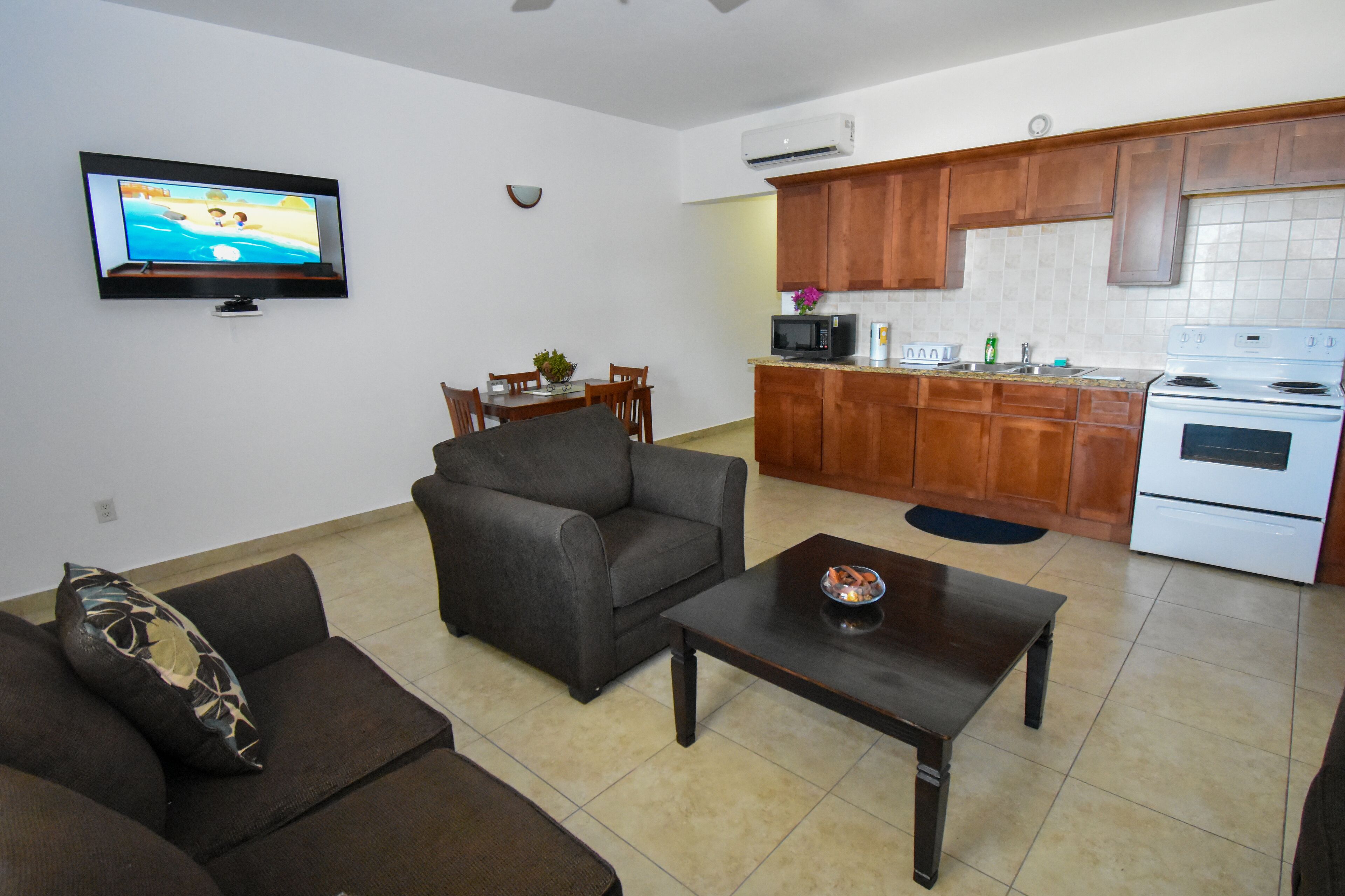 A living room with a sofa, a coffee table, and a TV on the wall.