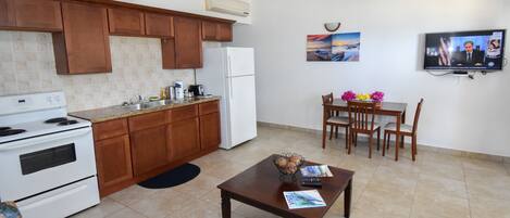 Una cocina moderna con armarios de madera, un refrigerador blanco y una zona de comedor con una mesa y sillas.